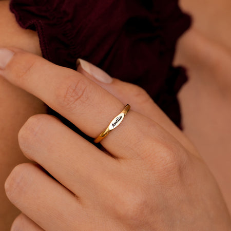 Skinny gold name ring worn on hand