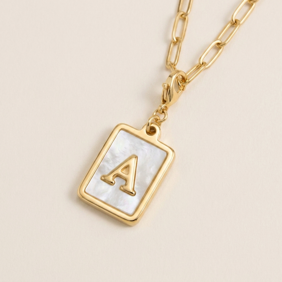 Mother of pearl initial card necklace flat lay detail — iridescent mother of pearl with raised gold letter A