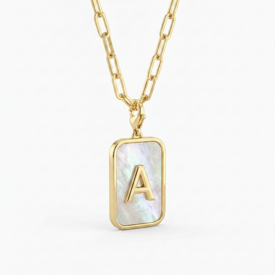 Mother of pearl initial card necklace hero — gold-framed pendant mother of pearl with raised gold letter A on paperclip chain, off-white neutral background matching reference