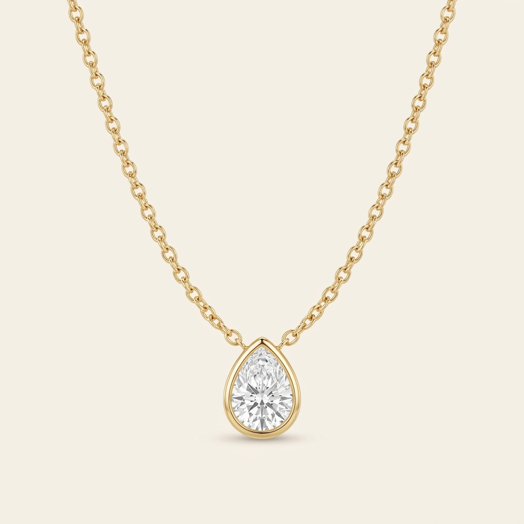 Diamond Teardrop Necklace — single strand cable chain U-curve, cream ivory background, gold bezel pear pendant