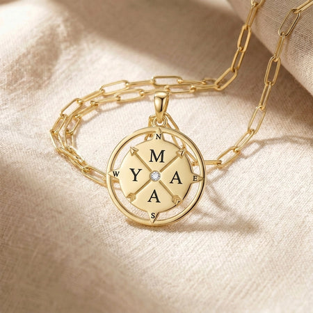 Compass pendant necklace gold flatlay on cream linen