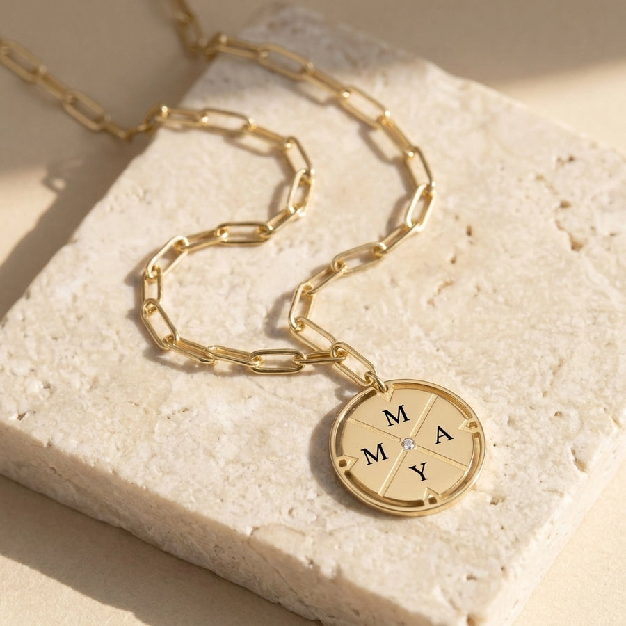 Compass pendant necklace gold resting on travertine stone