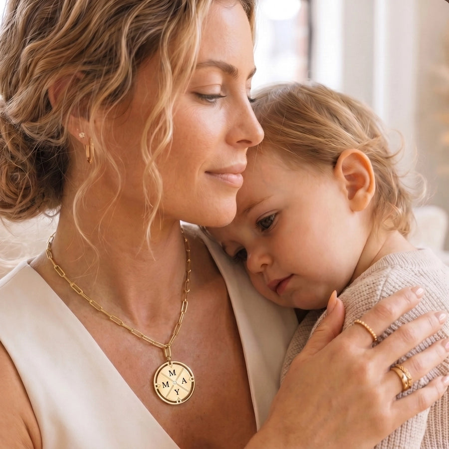 Mother holding baby wearing the gold compass pendant necklace