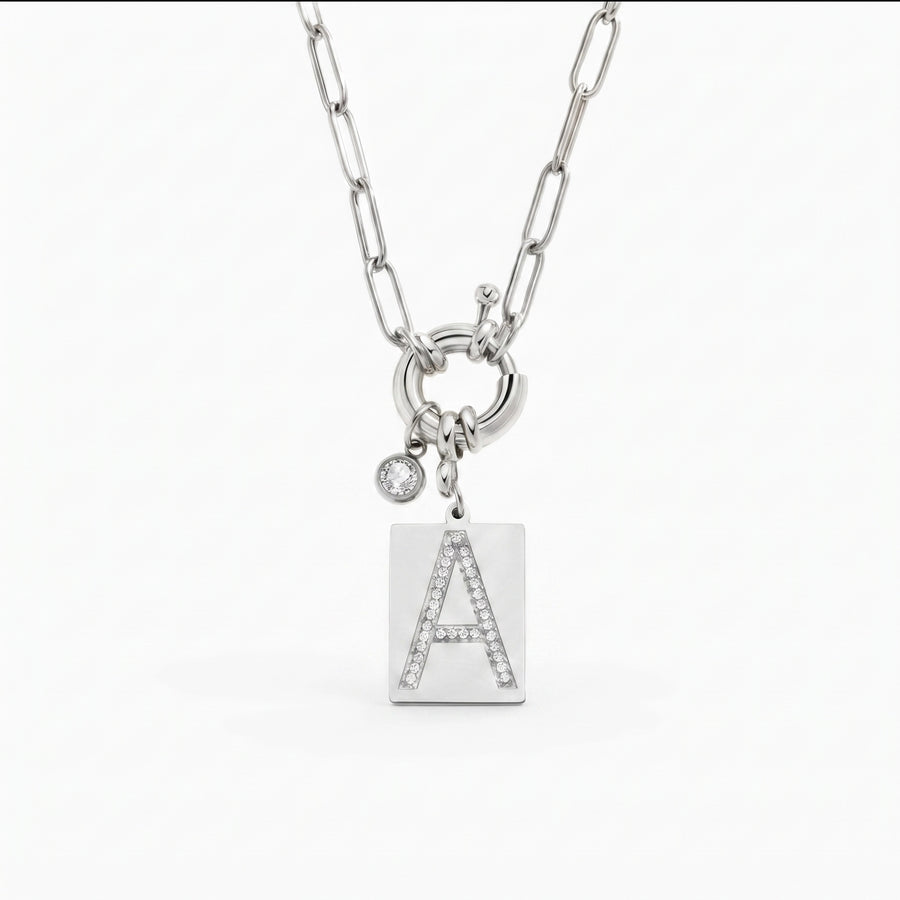 Pave Initial Pendant Necklace — silver tag pendant with pavé crystal letter A on silver paperclip chain, clean white background